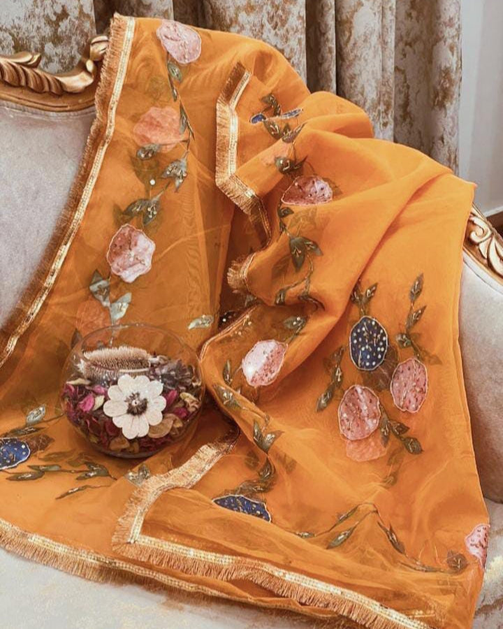 Orange embroidered fabric with floral patterns on a decorative surface
