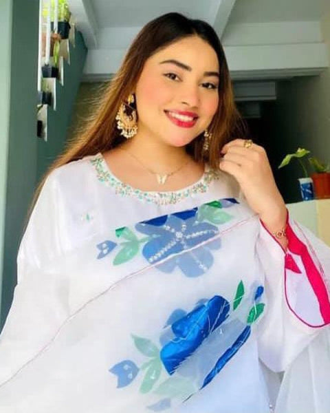 A woman wearing a traditional white and multicolored floral embroidered suit with a smile on her face.
