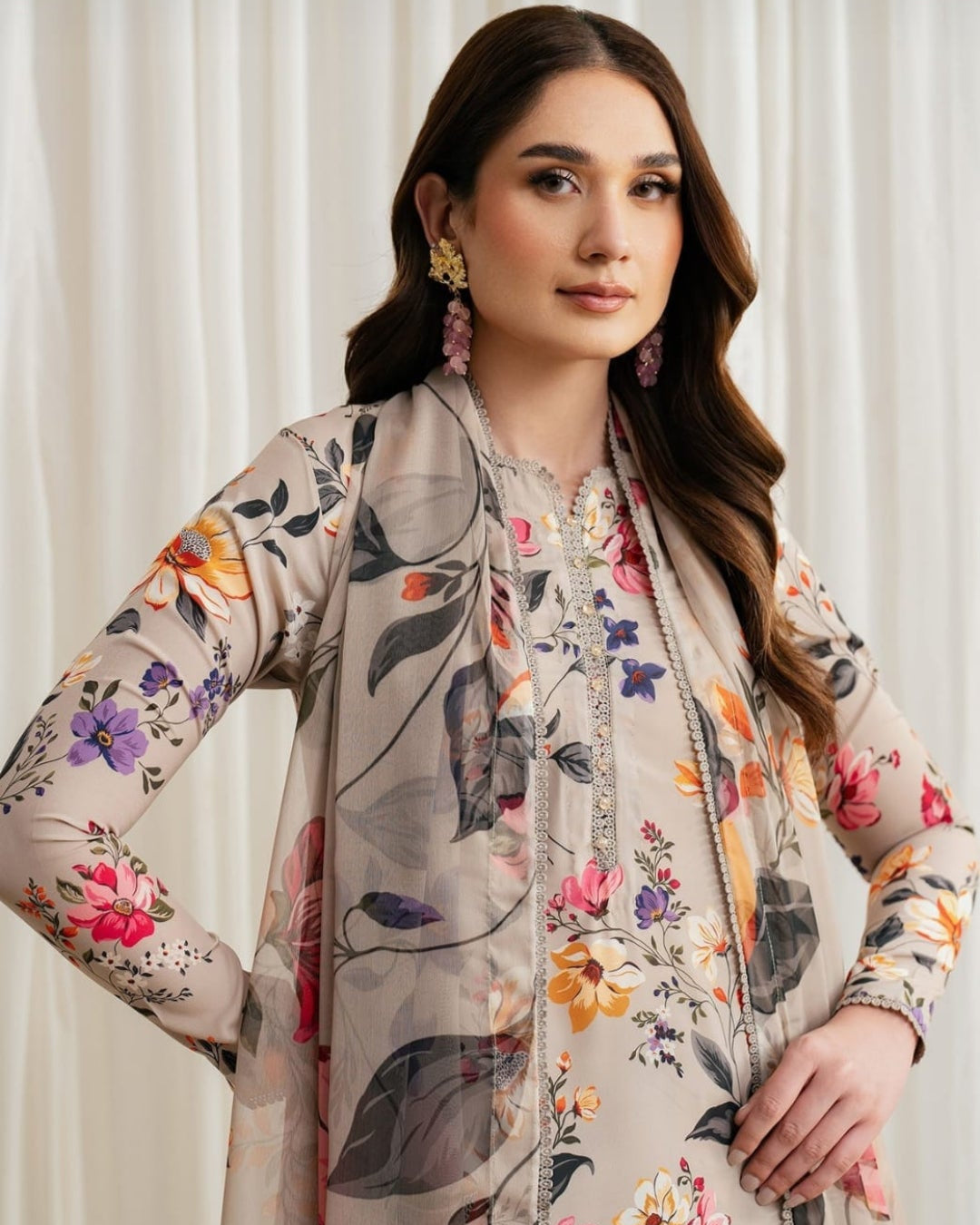 Woman wearing a floral dress with a matching shawl against a white curtain background